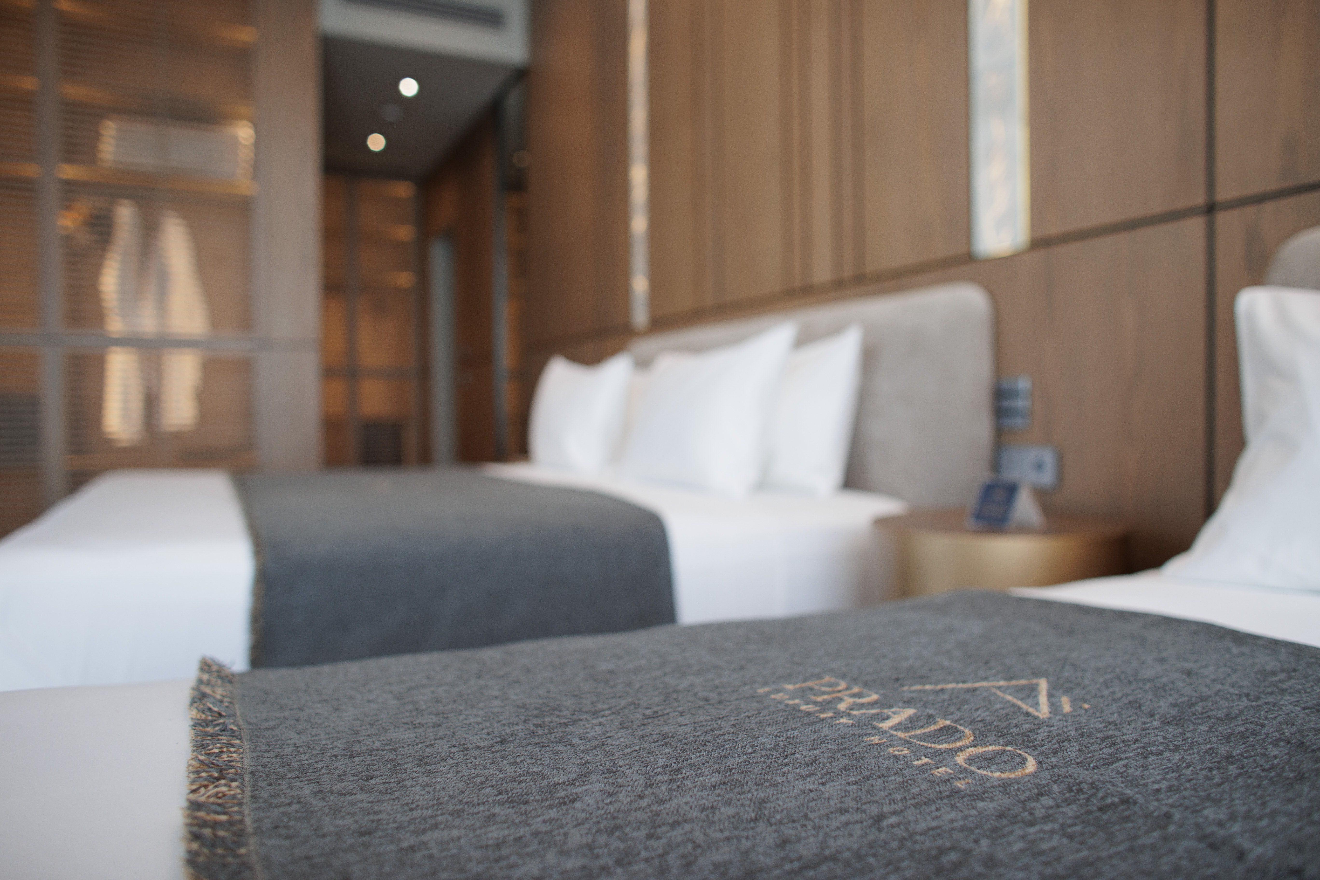 prado_luxury_hotel_deluxe_suite_bed_logo